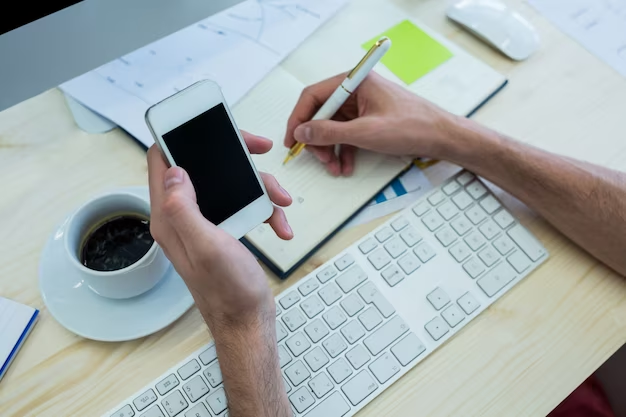 A man holds a smartphone in his hands and writes something in a diary