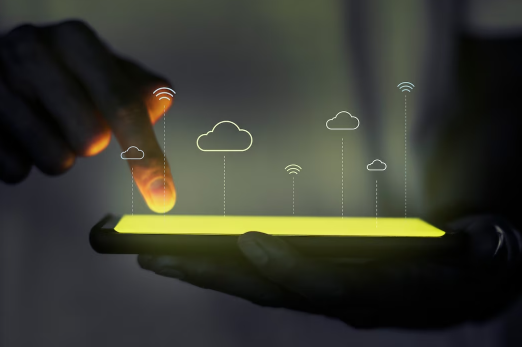 person holds phone with one hand, points with fingers on it with another, clouds above it